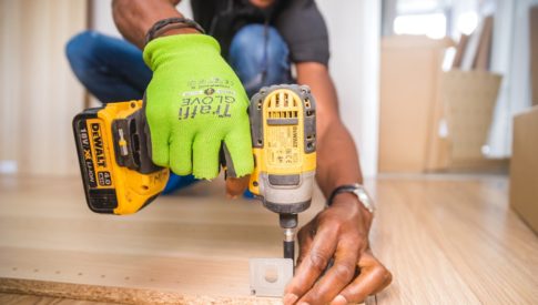 construction worker uses drill on board